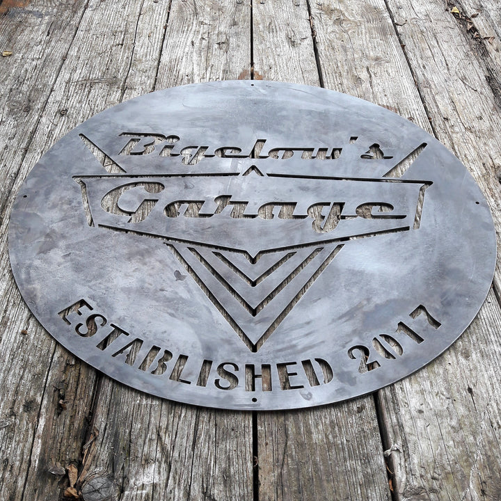 This is a rustic round metal garage sign which reads, "Bigelow's Garage, Established 2017"
