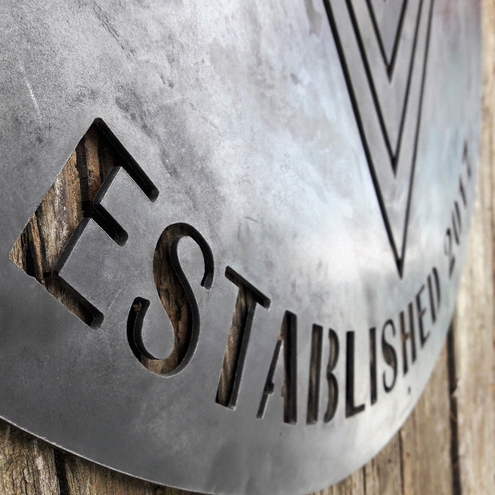 This is a rustic round metal garage sign which reads, "Bigelow's Garage, Established 2017"