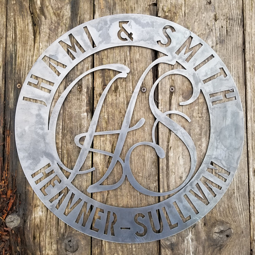 Round raw steel monogram with two lines of text and two letters in the center. The sign reads, " Jhami & Smith, Heavner-Sullivan"