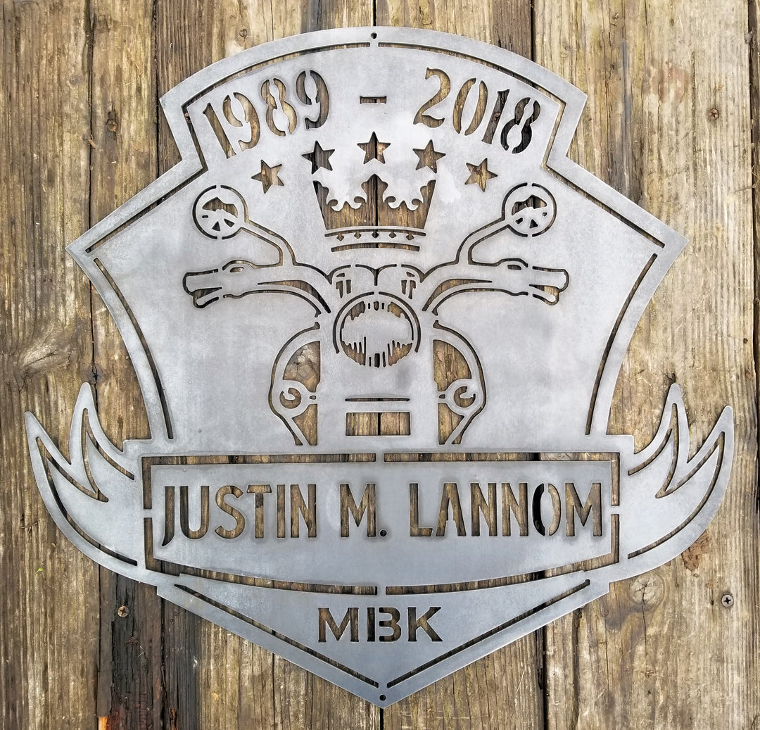 This is a memorial sign with an established year, dipicting an image of a motorcylce.  The bottom has a name and reads, "Justin M. Lannom".
