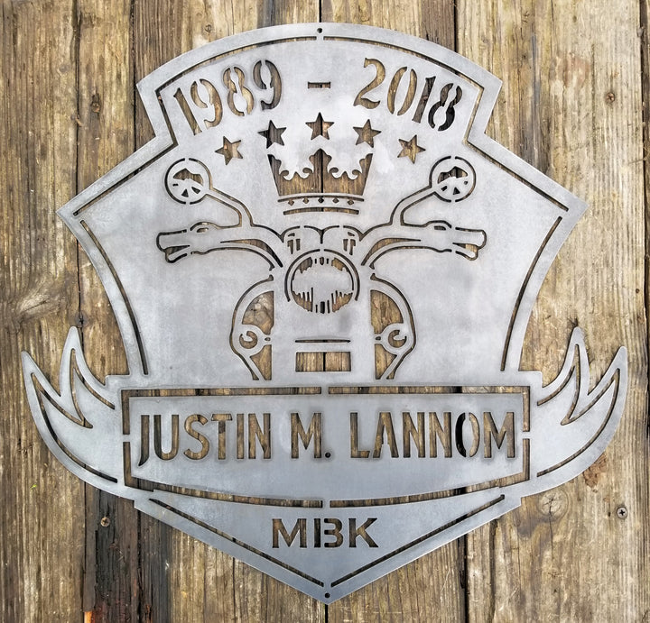 This is a memorial sign with an established year, dipicting an image of a motorcylce.  The bottom has a name and reads, "Justin M. Lannom".