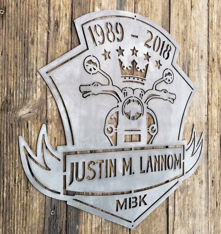 This is a memorial sign with an established year, dipicting an image of a motorcylce.  The bottom has a name and reads, "Justin M. Lannom".