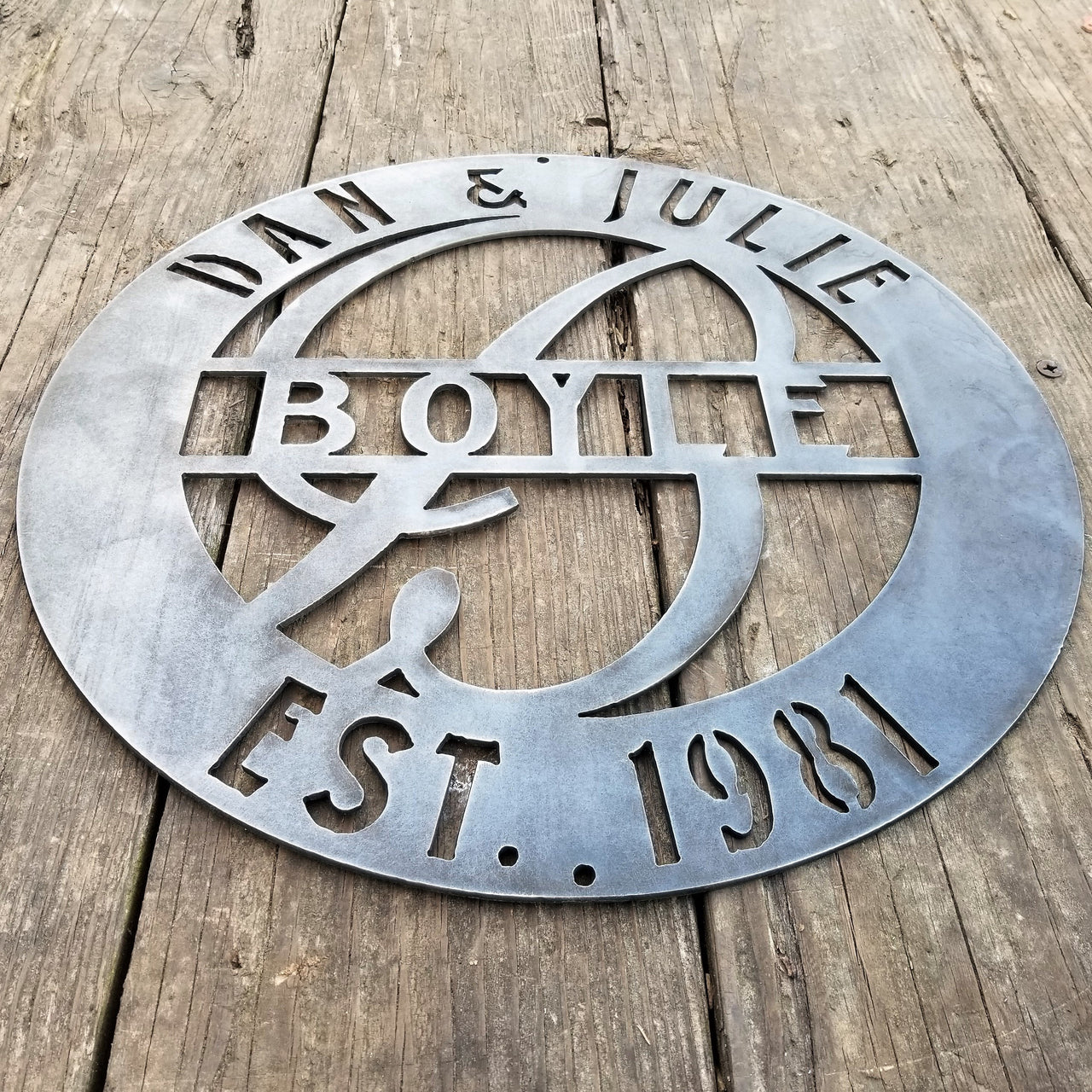 This is a round metal wedding monogram with 1/4"holes for hanging that reads, " Dan & Julie, Boyle, Established 1981"