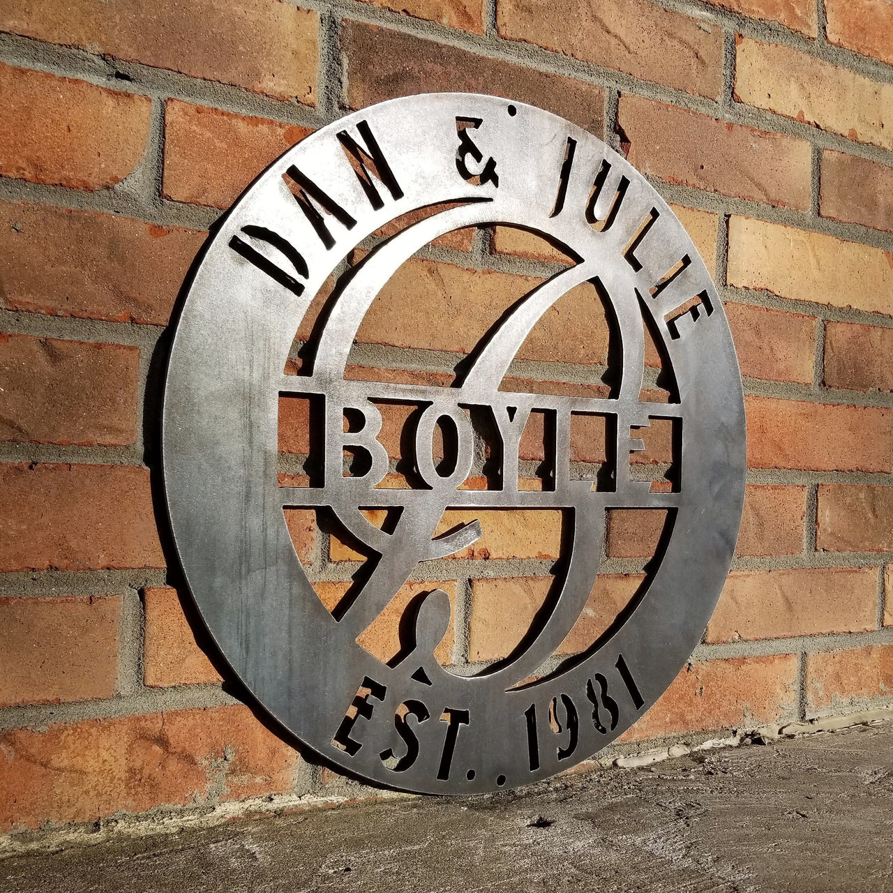 This is a round metal wedding monogram with 1/4"holes for hanging that reads, " Dan & Julie, Boyle, Established 1981"