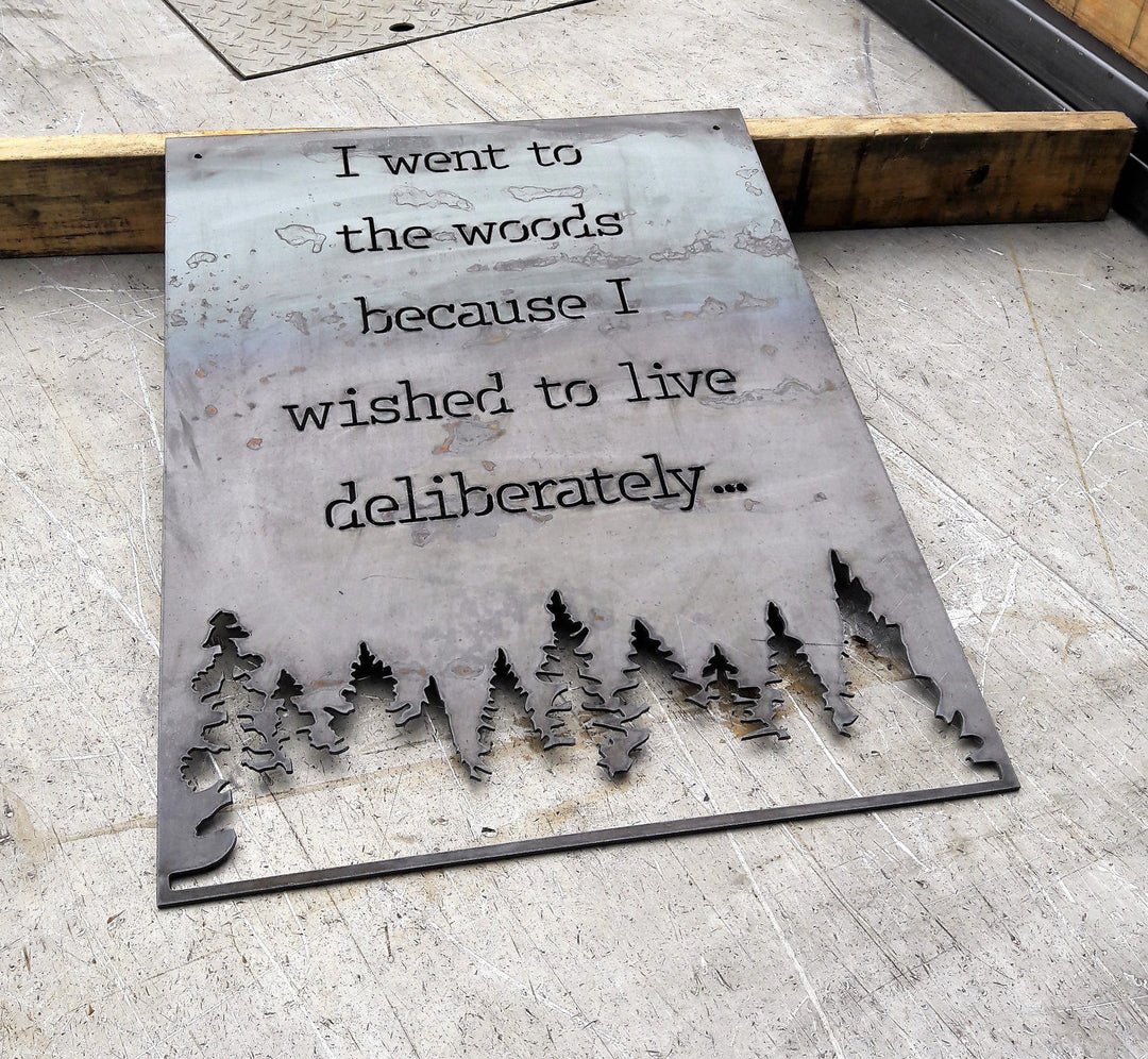 Rectangle metal sign, with a famous quote said by David Thoreau which reads, "I Went to the Woods because I Wished to Live Deliberately..."