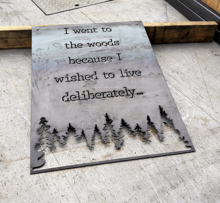 Rectangle metal sign, with a famous quote said by David Thoreau which reads, "I Went to the Woods because I Wished to Live Deliberately..."