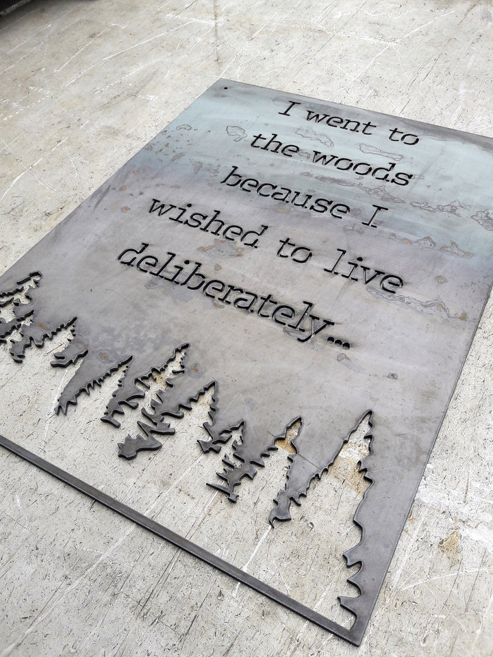 Rectangle metal sign, with a famous quote said by David Thoreau which reads, "I Went to the Woods because I Wished to Live Deliberately..."