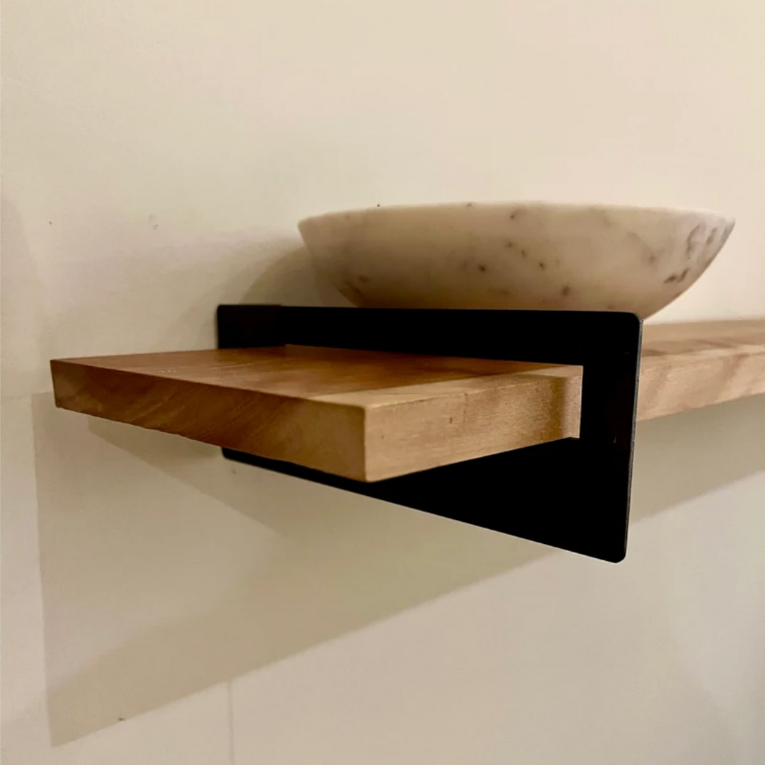 Floating shelf bracket holding wood board on wall
