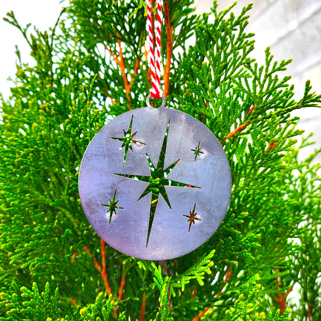 Star of Bethlehem metal ornament hanging on evergreen
