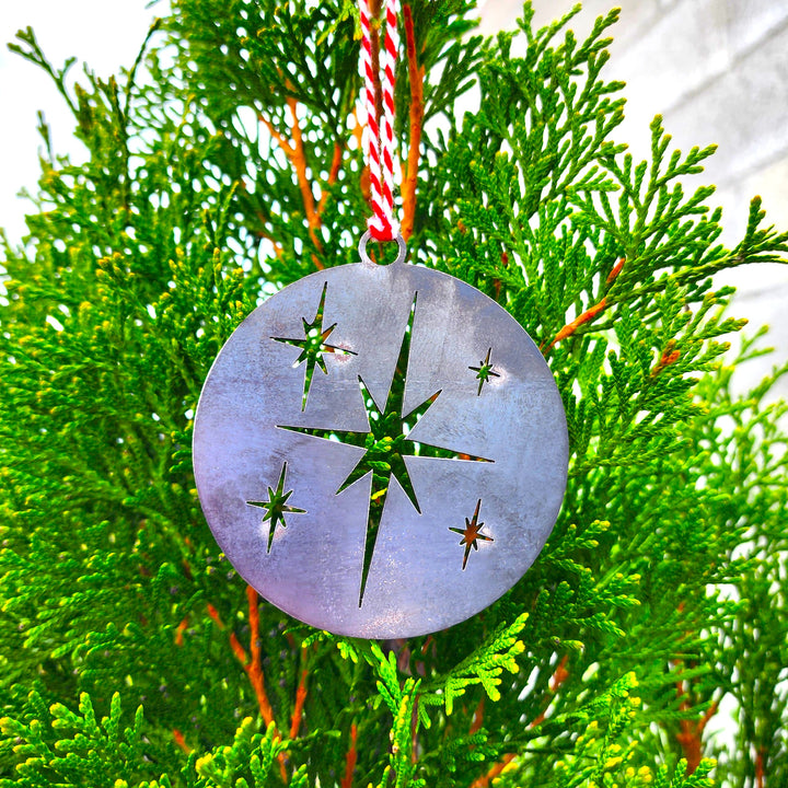 Star of Bethlehem metal ornament hanging on evergreen