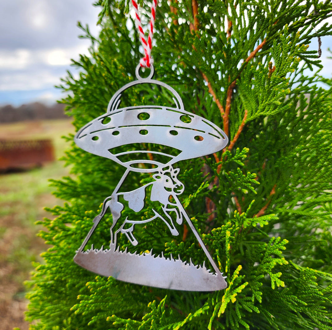 ufo cow abduction metal ornament hanging on evergreen
