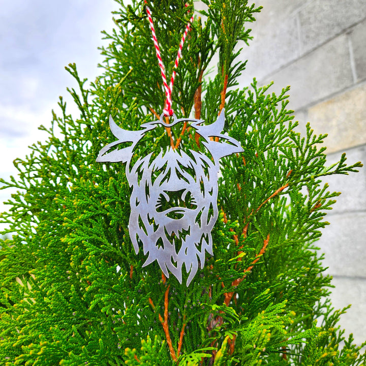 highland cow metal ornament hanging on evergreen