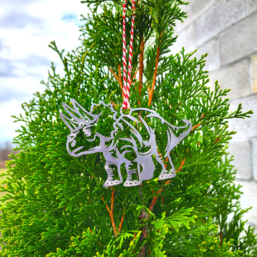 triceratops dinosaur metal ornament hanging on evergreen