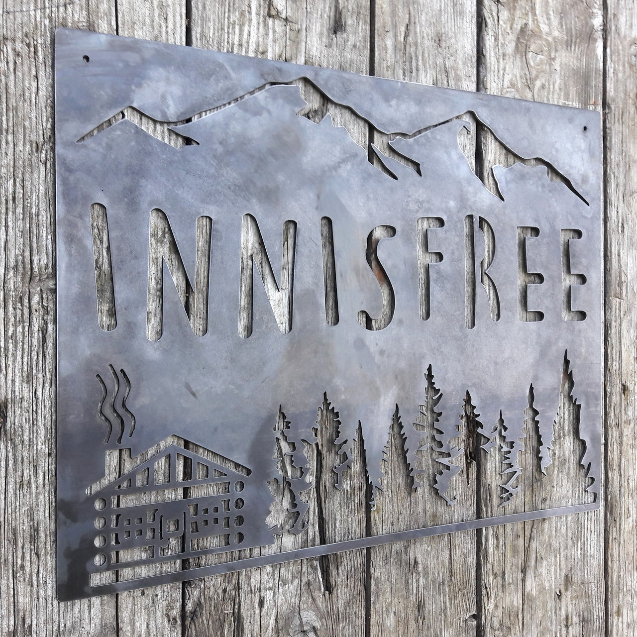 This sign is displays a mountain range in the background with a forest and cabin. The sign reads, "INNISFREE".