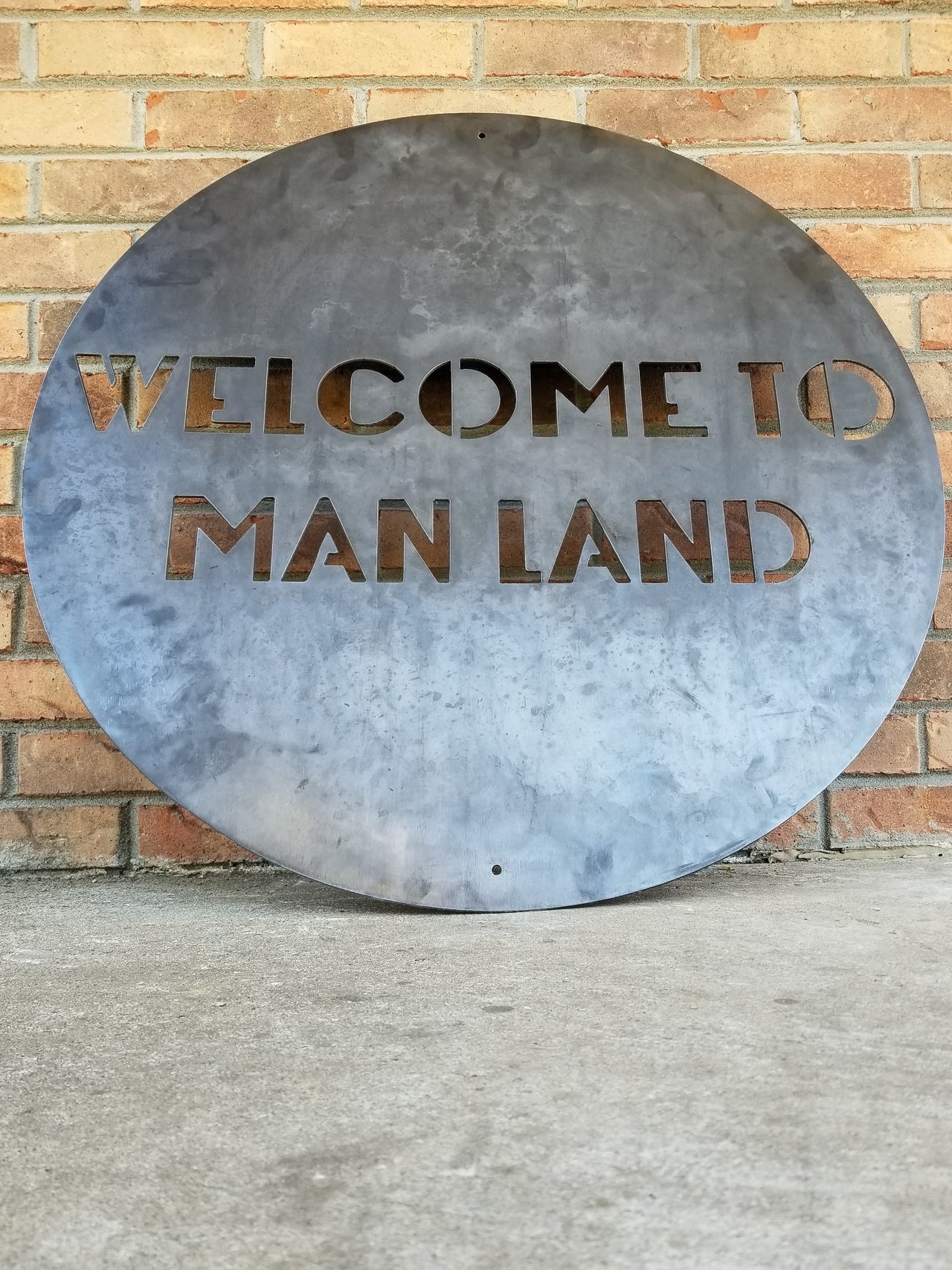 Round Personalized metal sign that reads, "Welcome To Man Land".
