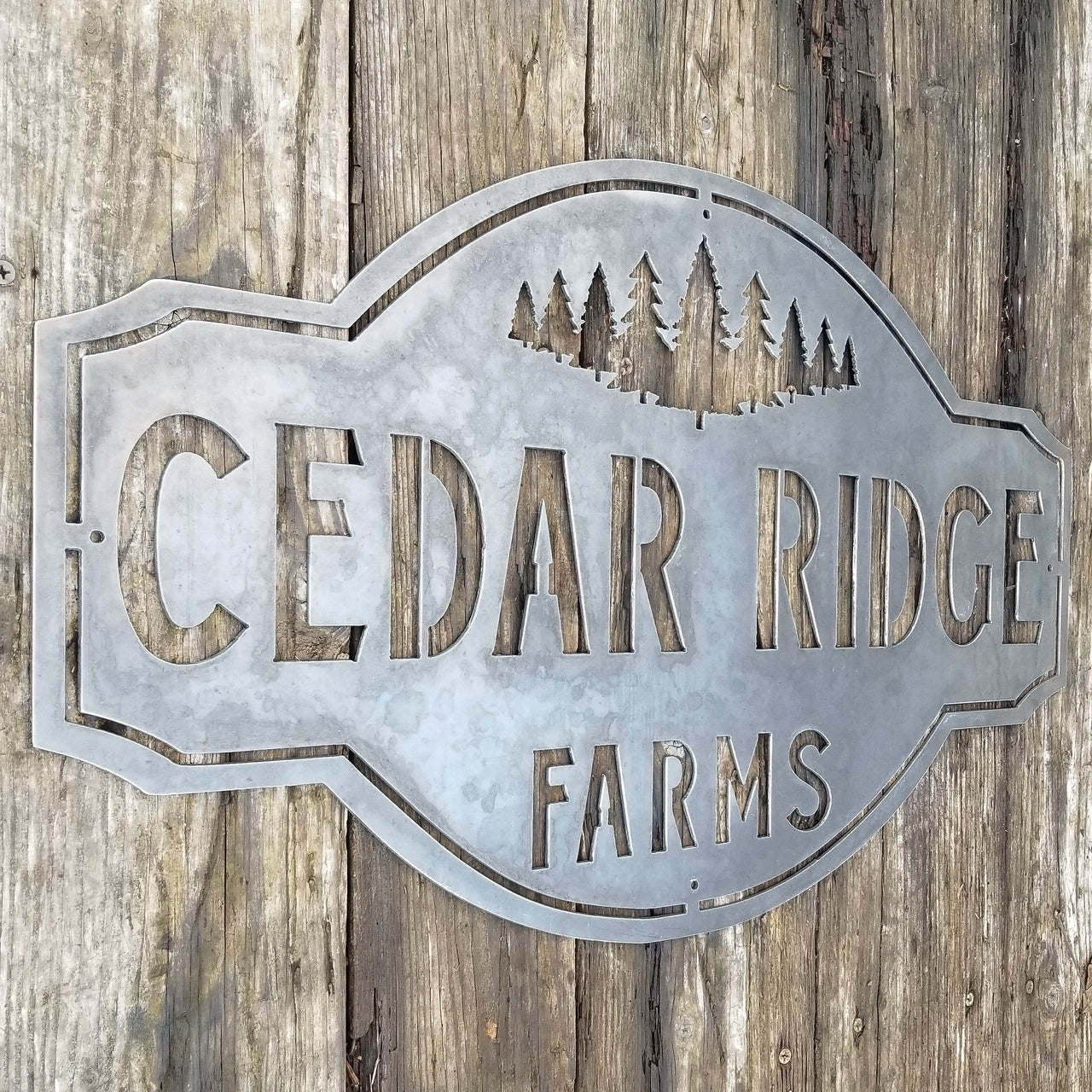 This is a rustic metal sign showcasing an image of trees at the top. The sign reads, "Cedar Ridge Farms".