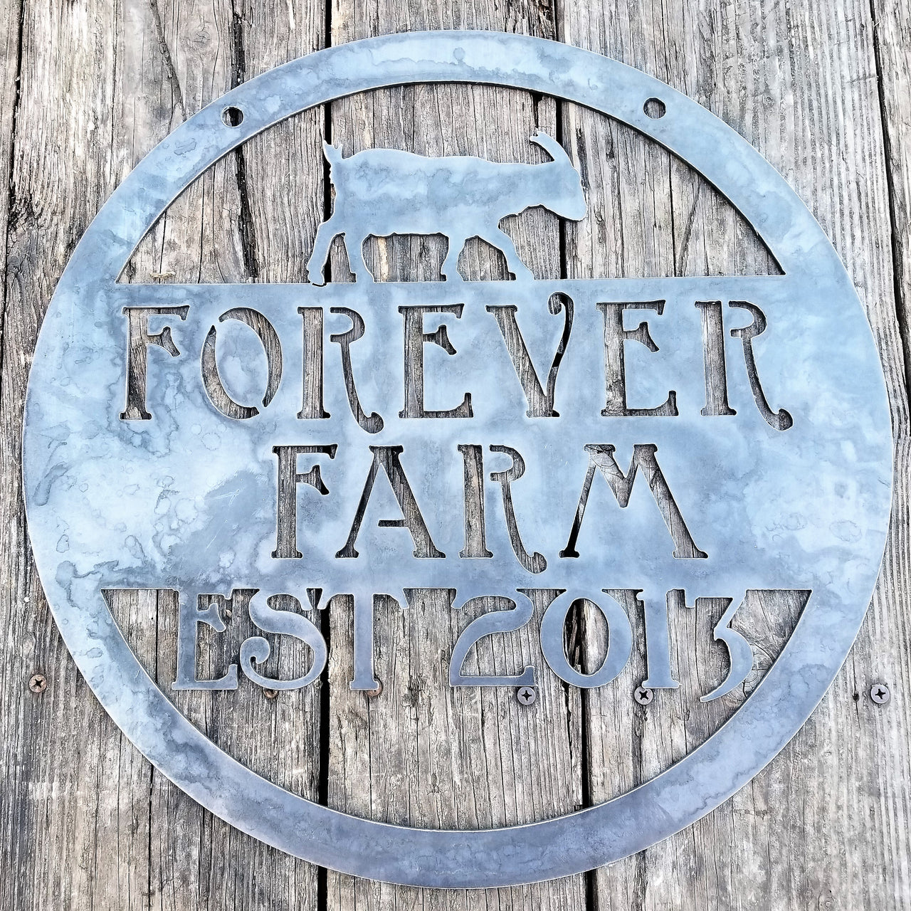 This is a custom round metal sign that features a goat and reads from the top down, "Forever Farm Est. 2013"