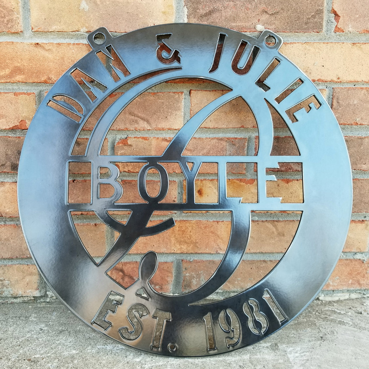 This is a round outdoor clear powder coated monogram with 1/2" dog ears for hanging that reads, " Dan & Julie, Boyle, Established 1981"