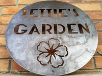 Thumbnail for This is a round sign with an image of a flower below two lines of text which read, 