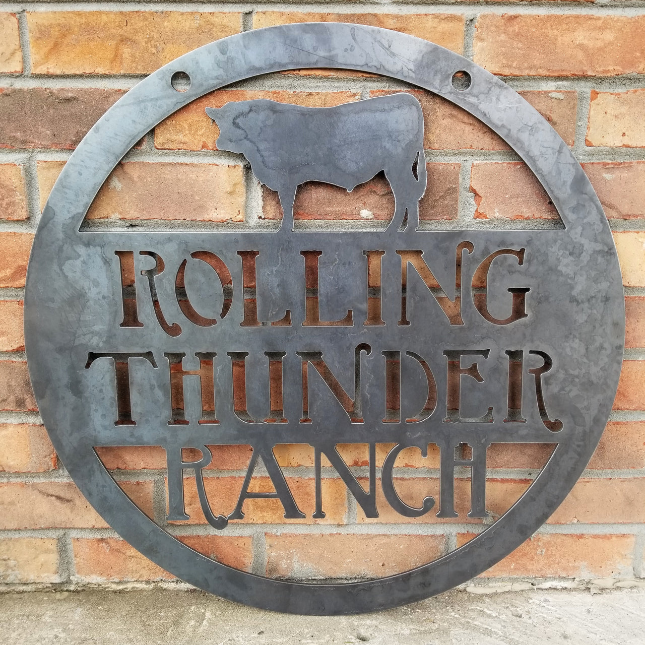 This is a custom round metal sign that features a steer and reads from the top down, "Rolling Thunder Ranch"
