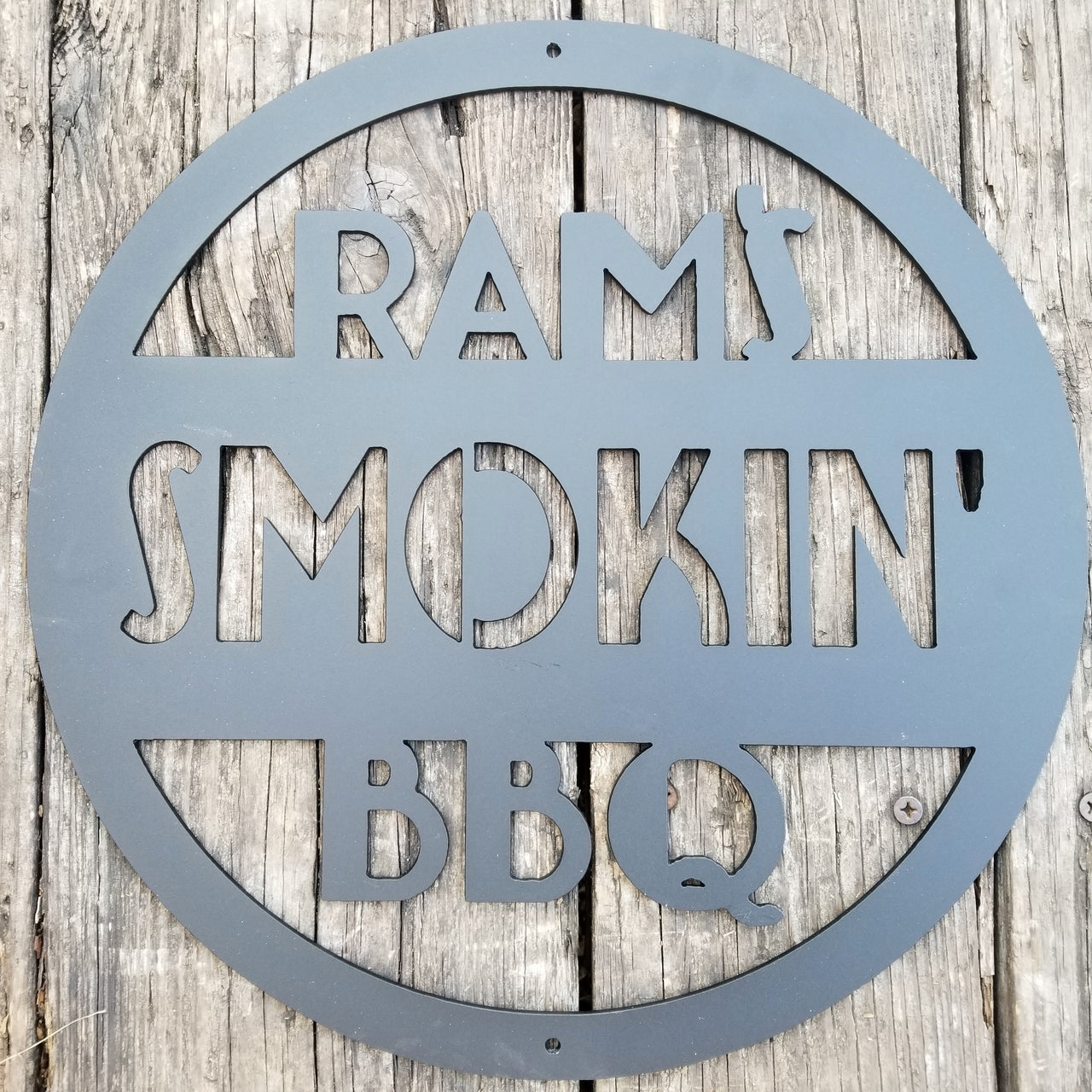 This is a round art deco. sign that has three lines of text. The sign reads, " Rams Smokin' BBQ""