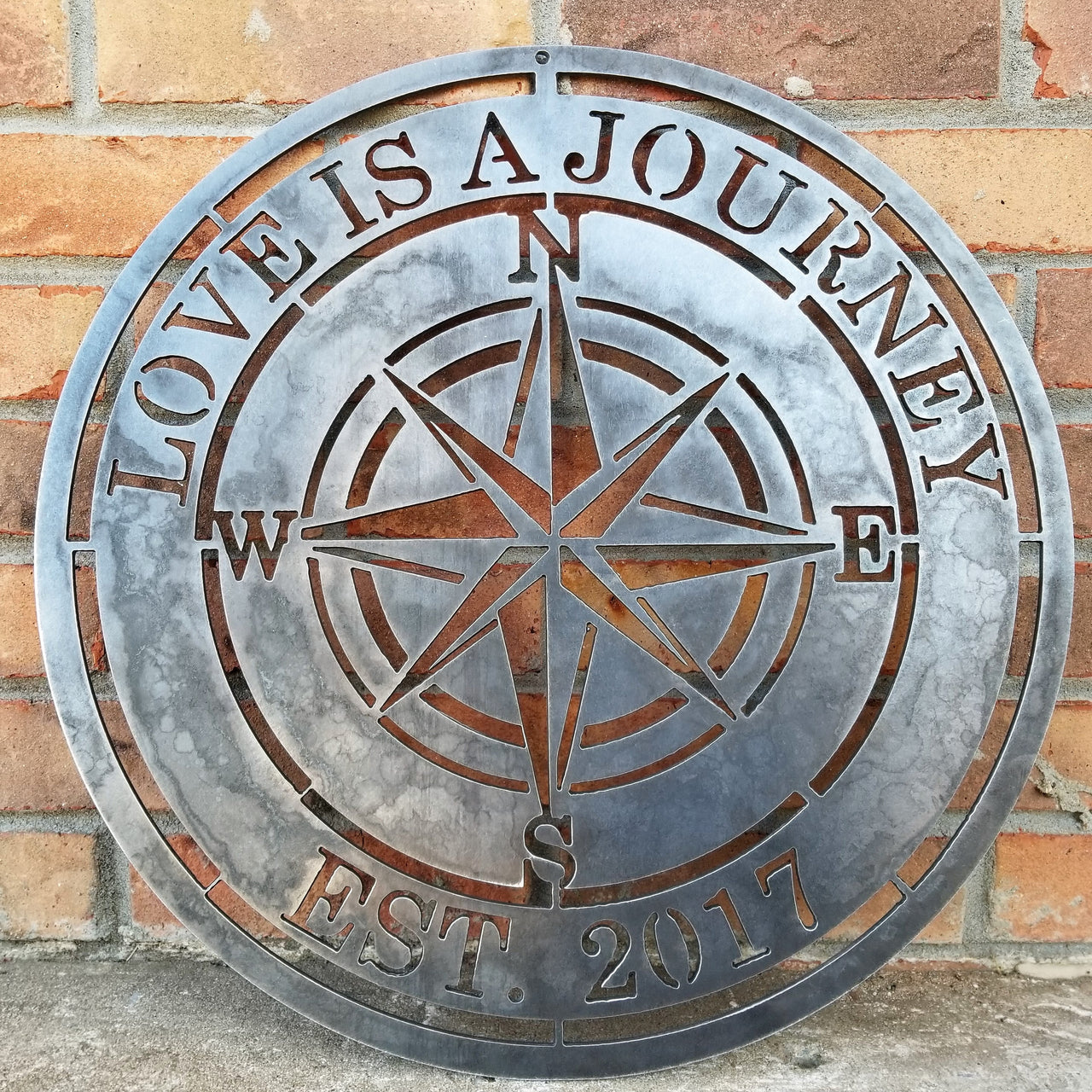 A nautical compass rose which reads, "Love is A Journey".