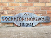 Thumbnail for This is a raw steel, custom metal sign.  At the top of the sign is an image of mountains. There is two lines of text on this sign which reads, 
