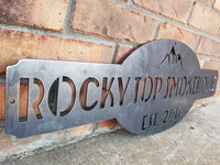 Thumbnail for This is a raw steel, custom metal sign.  At the top of the sign is an image of mountains. There is two lines of text on this sign which reads, 
