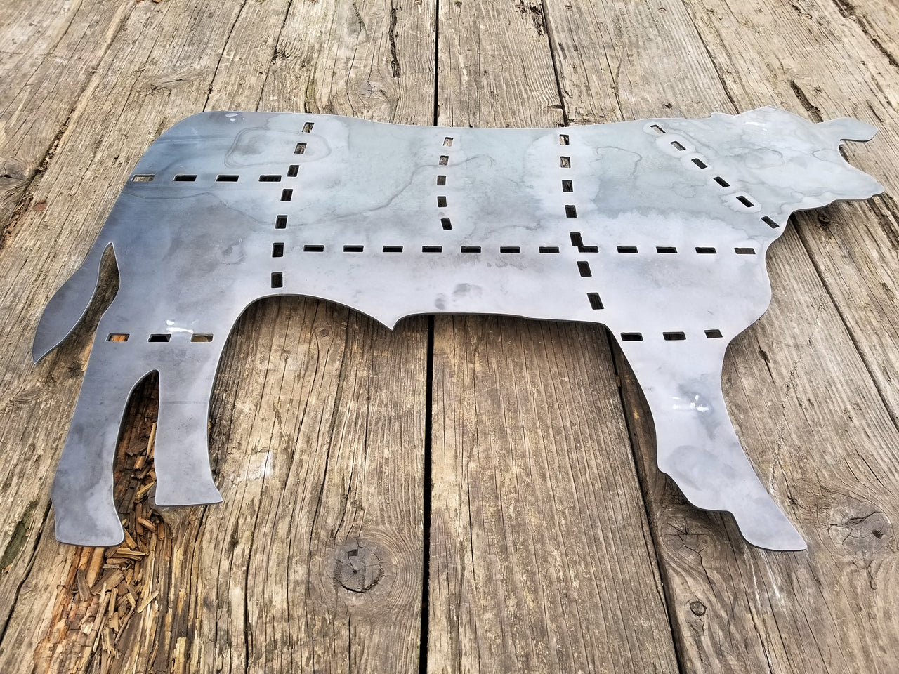 This is a metal sign in the shape of a cow with the cuts of beef outlined.
