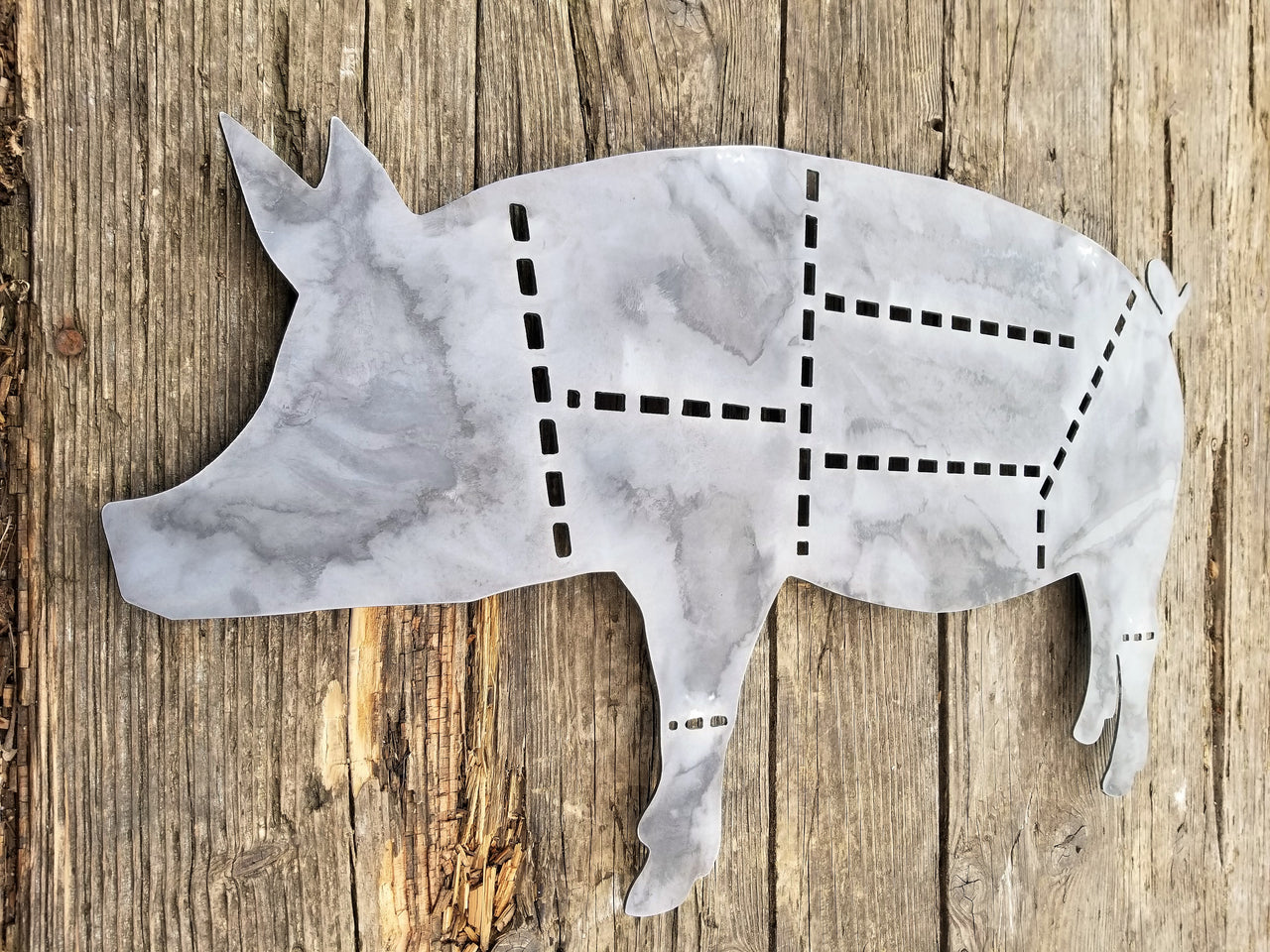 This sign is in the shape of a pig and dotted lines separate the cuts of pork