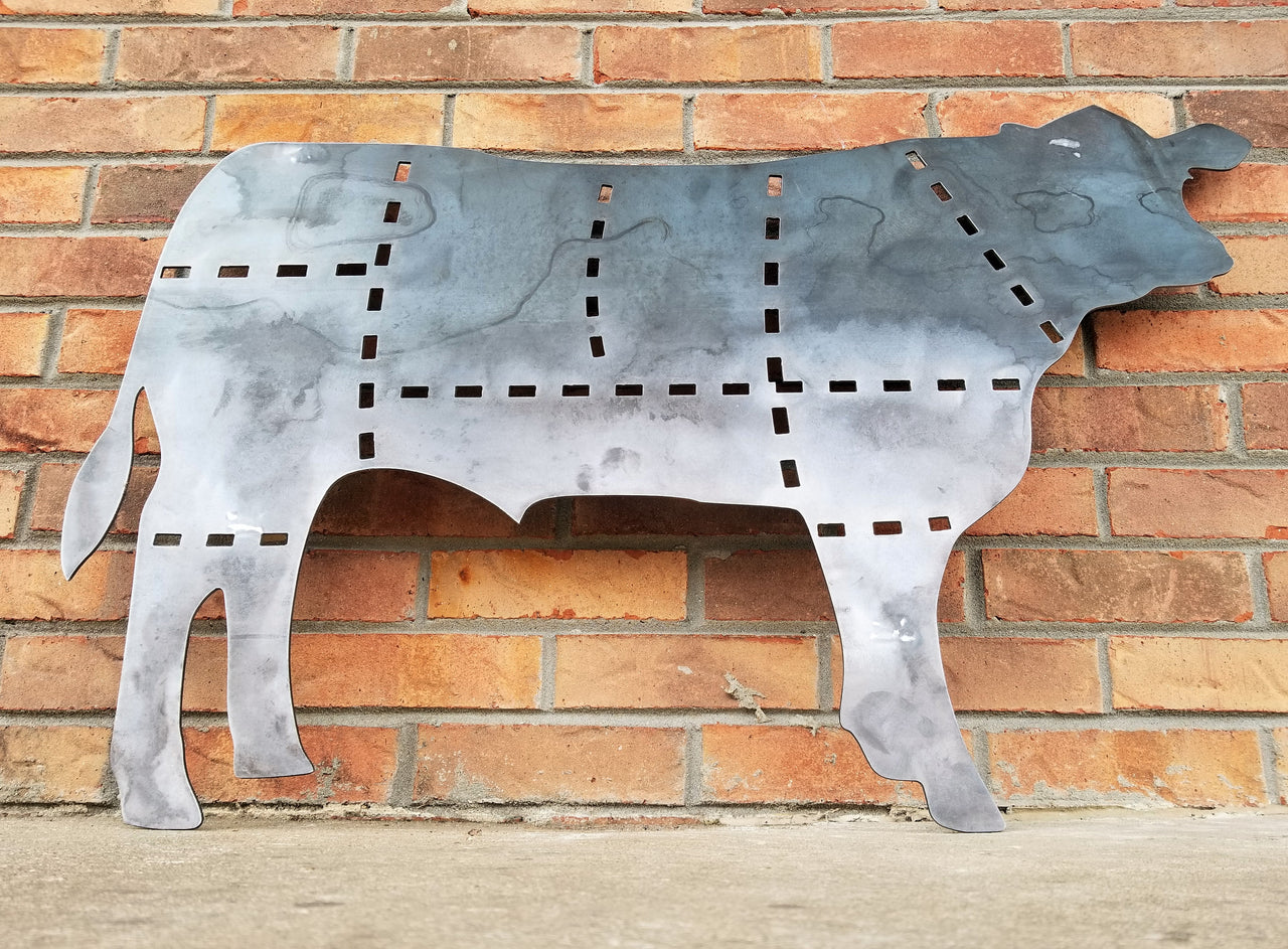This is a metal sign in the shape of a cow with the cuts of beef outlined.