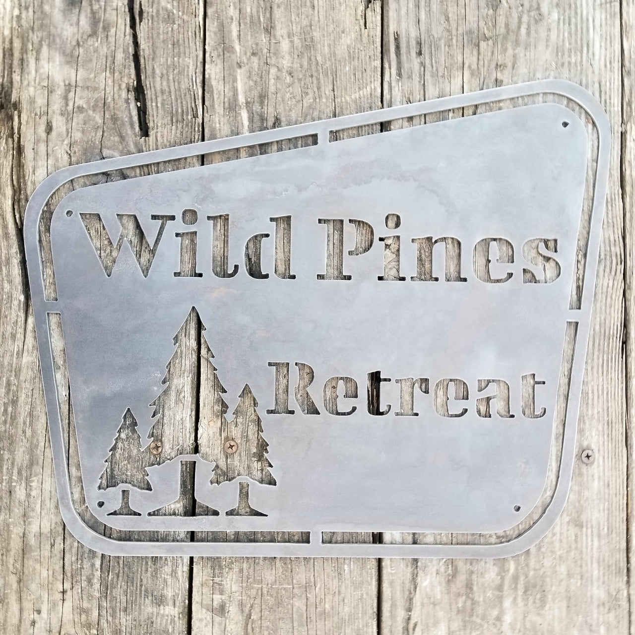 This sign has a vintage design and depicts a group of trees. It reads, "Wild Pines Retreat".