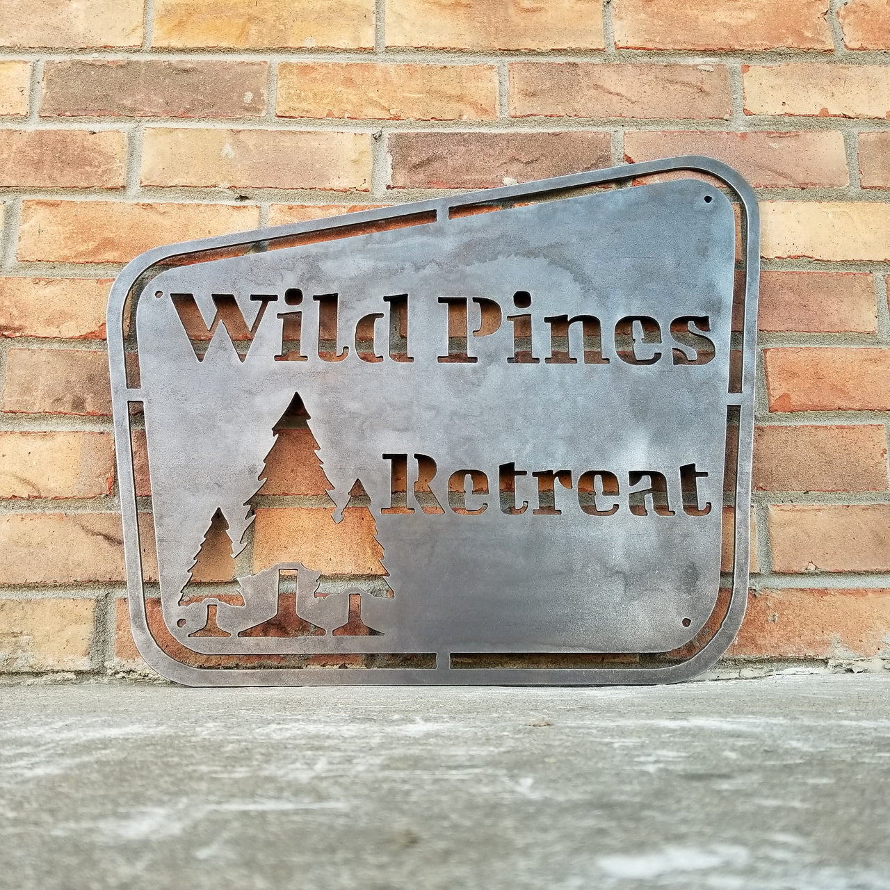 This sign has a vintage design and depicts a group of trees. It reads, "Wild Pines Retreat".