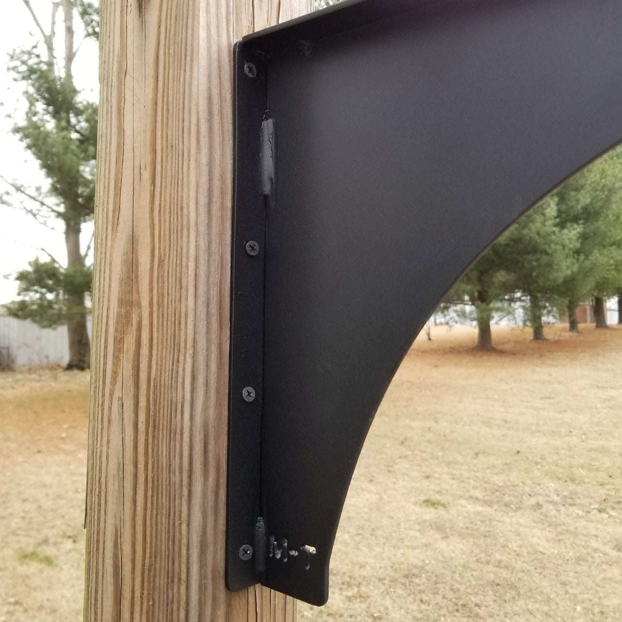 This is a close up of a black powder coated bracket for hanging a sign. It has six 1/4" holes for mounting.