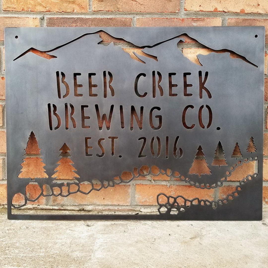This sign showcases a mountain background with trees and a creek. The sign reads, " Beer Creek Brewing Co. Est. 2016".