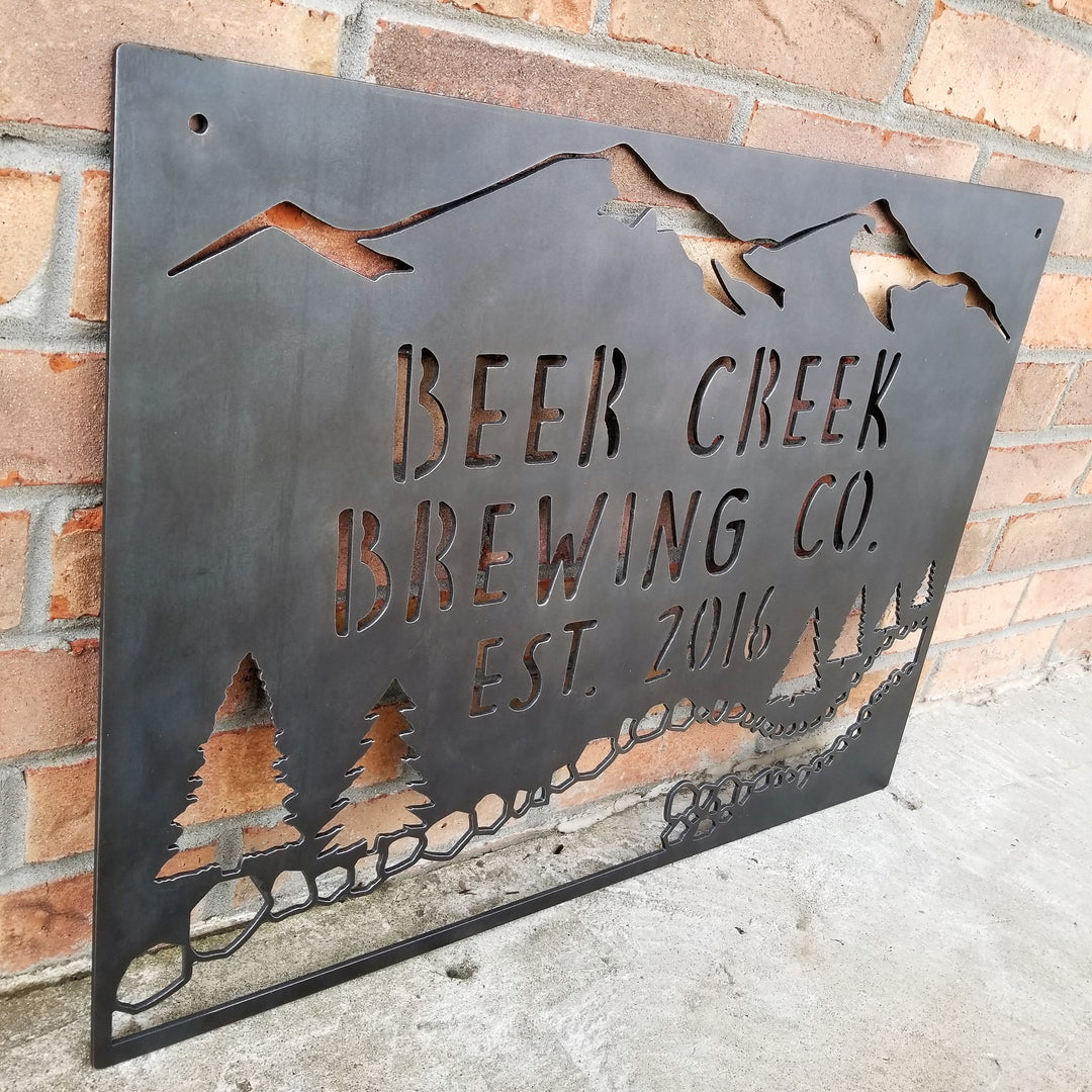 This sign showcases a mountain background with trees and a creek. The sign reads, " Beer Creek Brewing Co. Est. 2016".