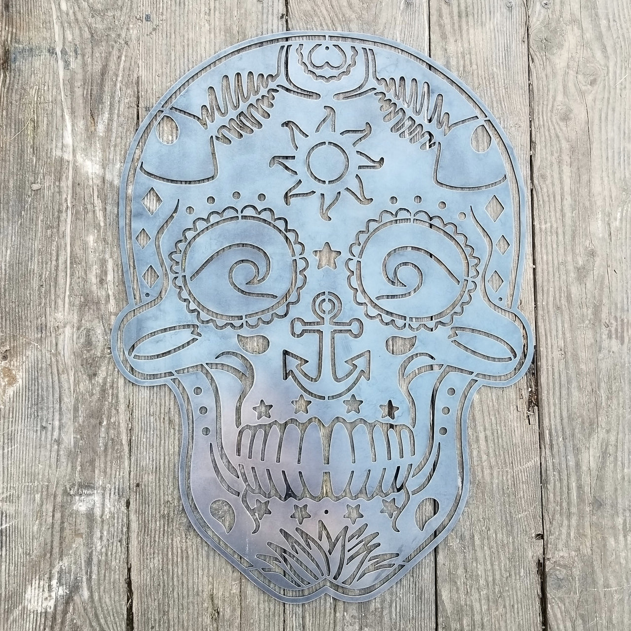 This sign is in the shape of a sugar skull. It is water themed with waves, fish bones, anchors and more.
