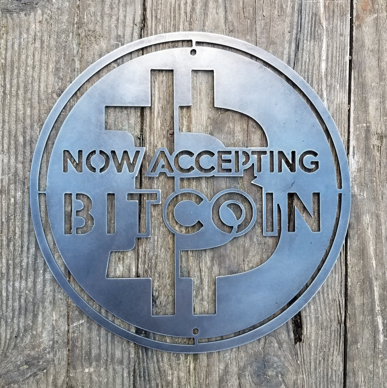 This is a round sign that reads, "Now Accepting Bitcoin".