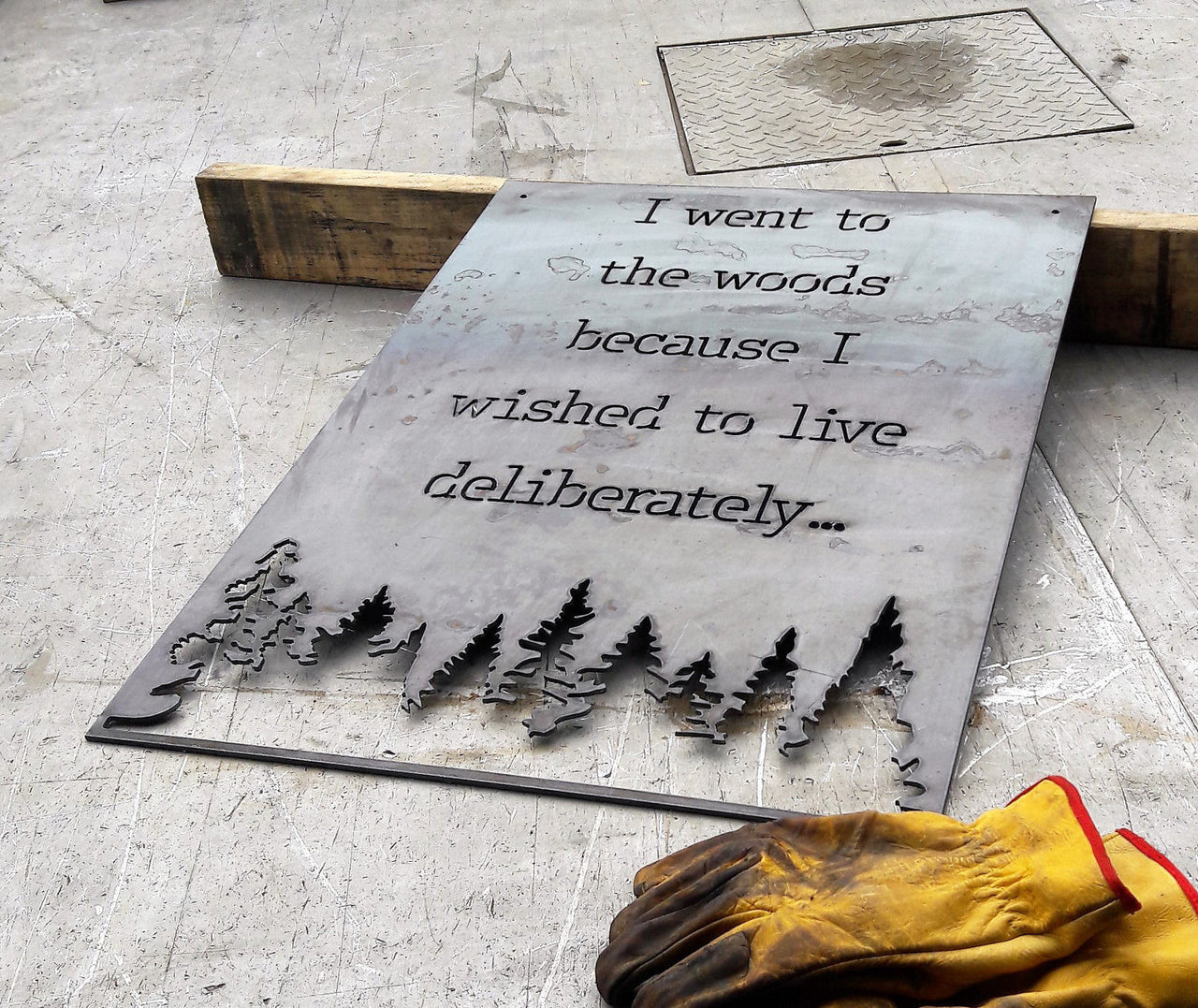 Rectangle metal sign, with a famous quote said by David Thoreau which reads, "I Went to the Woods because I Wished to Live Deliberately..."