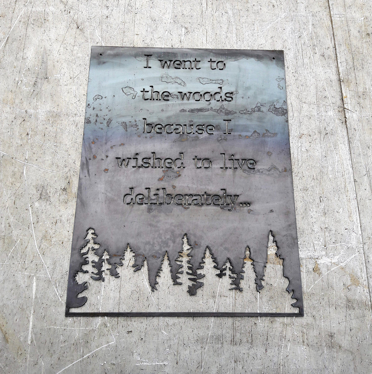 Rectangle metal sign, with a famous quote said by David Thoreau which reads, "I Went to the Woods because I Wished to Live Deliberately..."