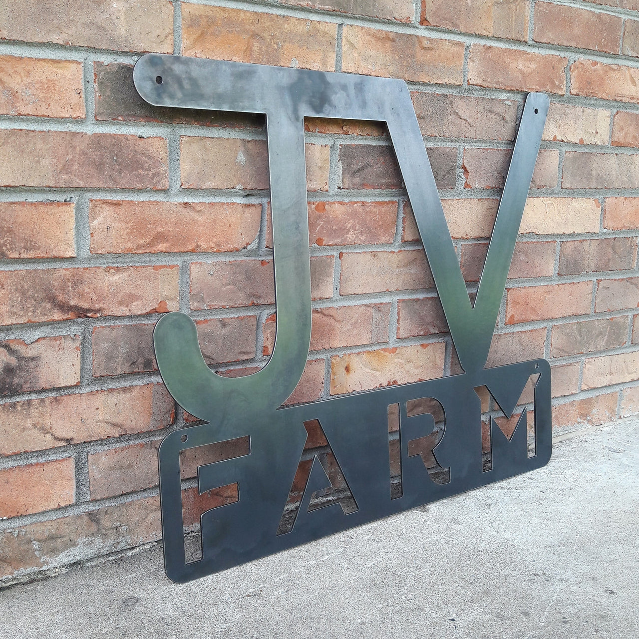 This metal sign has two initials at the top followed by a block of text. It reads, "JV Farm"