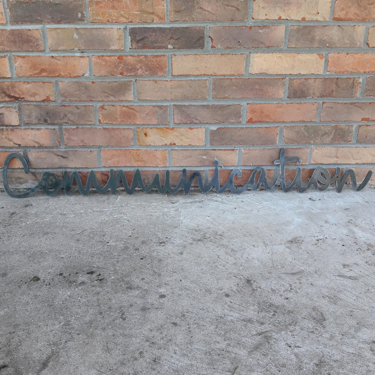 This custom metal sign is a cursive word and reads, "Communication"