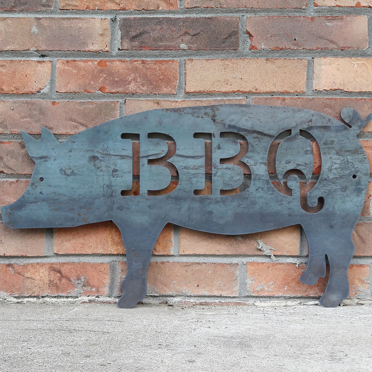 This is a metal sign in the shape of pig with two 1/4" mounting holes. The sig reads, "BBQ"