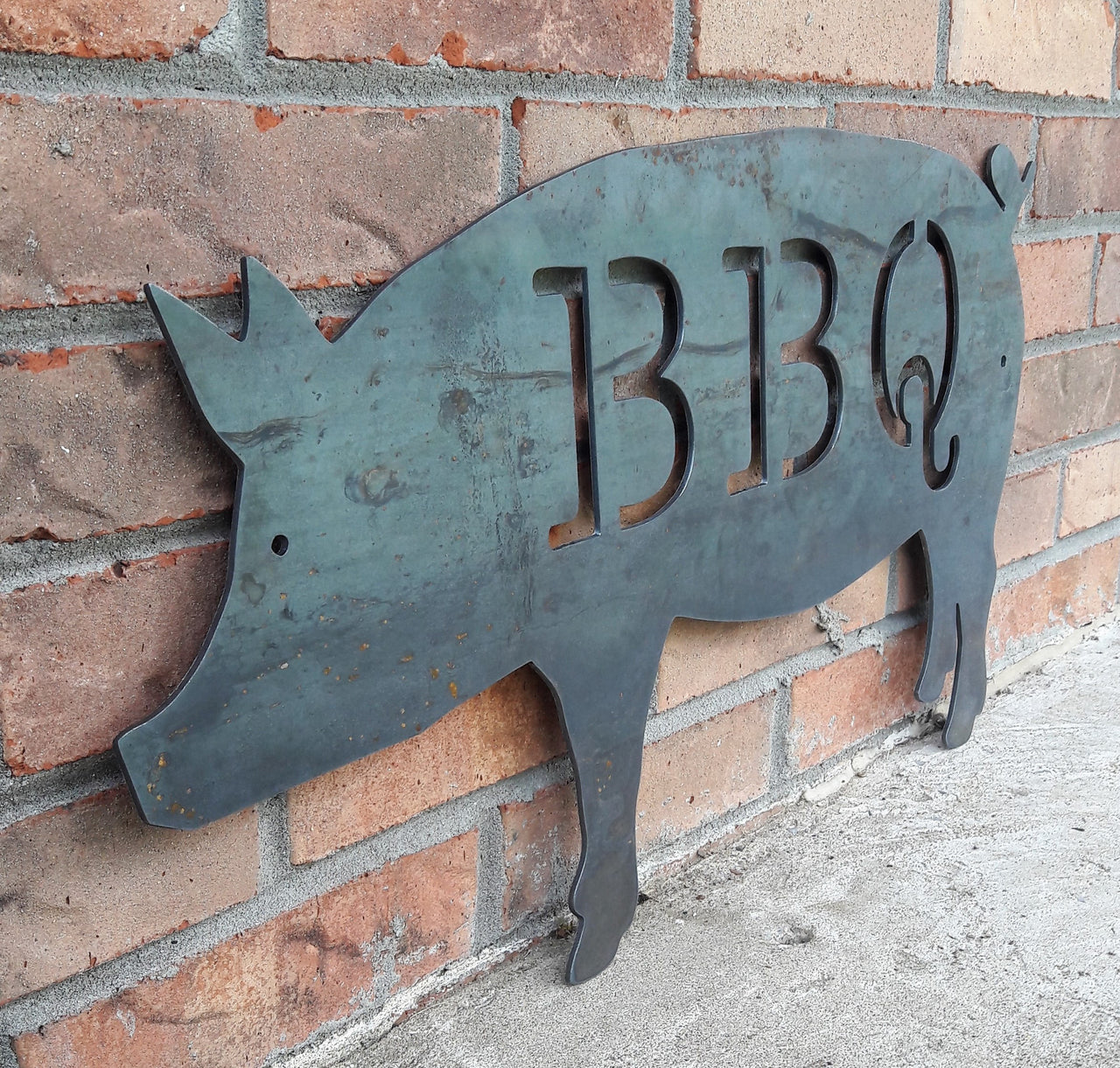 This is a metal sign in the shape of pig with two 1/4" mounting holes. The sig reads, "BBQ"