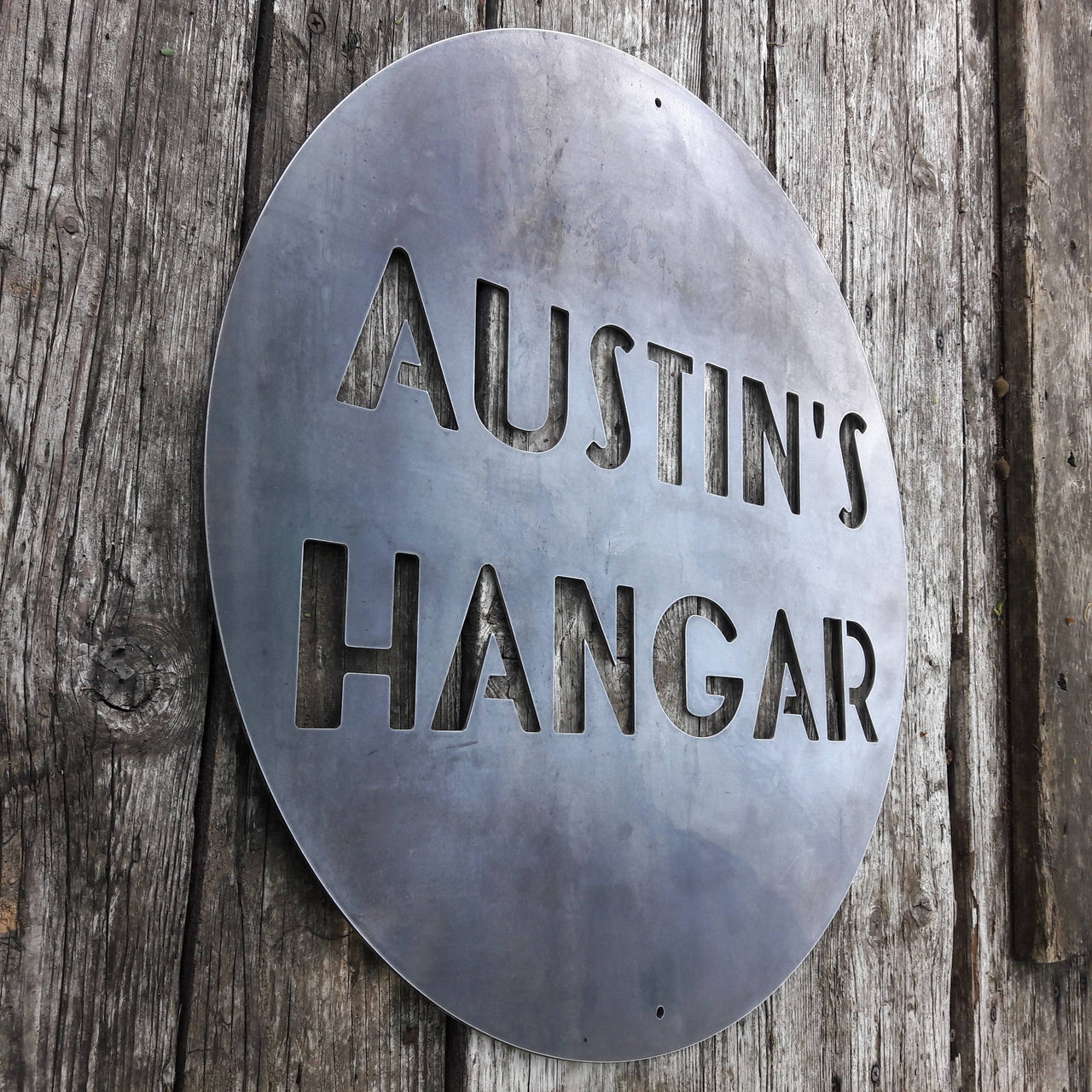 Round Personalized metal sign that reads, "Austin's Hangar"