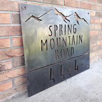 Thumbnail for Rectangular metal sign with half inch hanging holes. There is a mountain range at the top followed by three lines of text and then a number. The sign reads, 