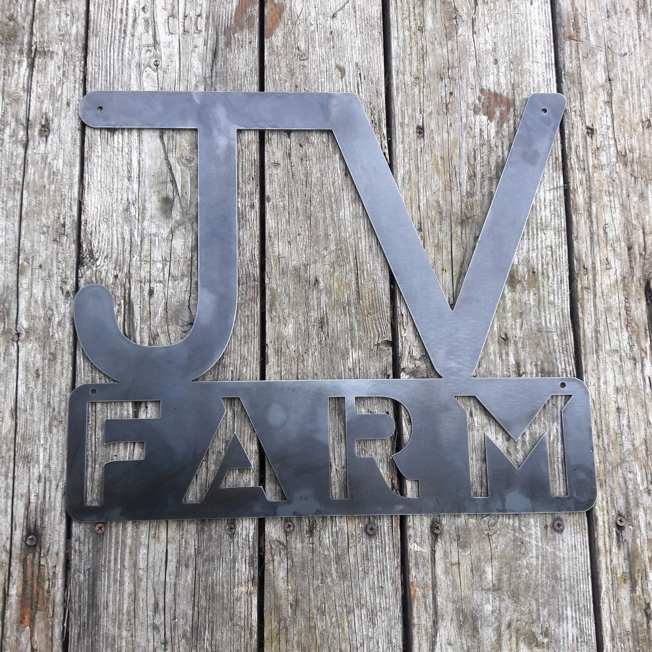 This metal sign has two initials at the top followed by a block of text. It reads, "JV Farm"