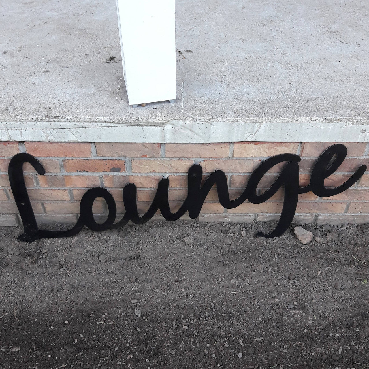 This is a custom metal cursive sign that is powder coated black and reads' " Lounge".